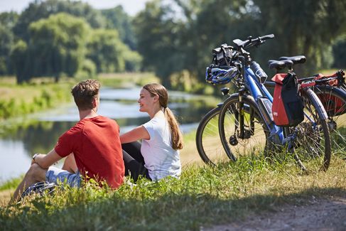 Zwei Radfahrer sitzen am Wiesenrand